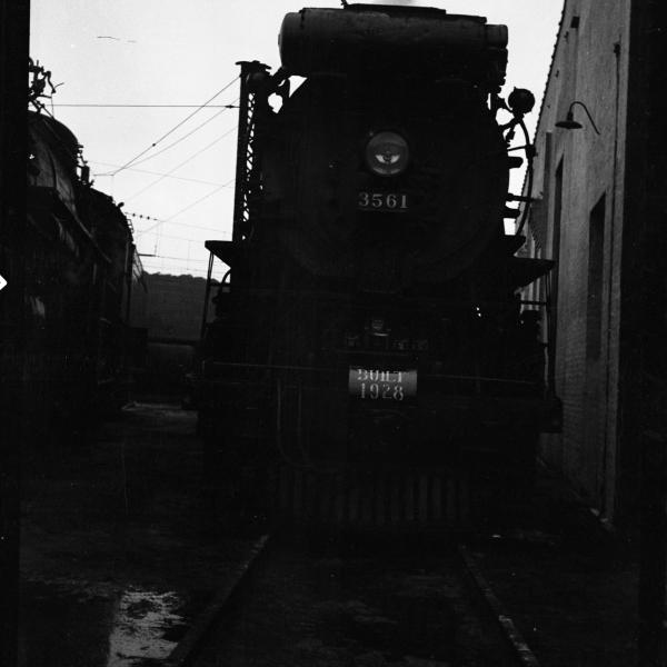 Front view of locomotive alongside of roundhouse wall while on display for rail fans: sign atop pilot-beam built 1928