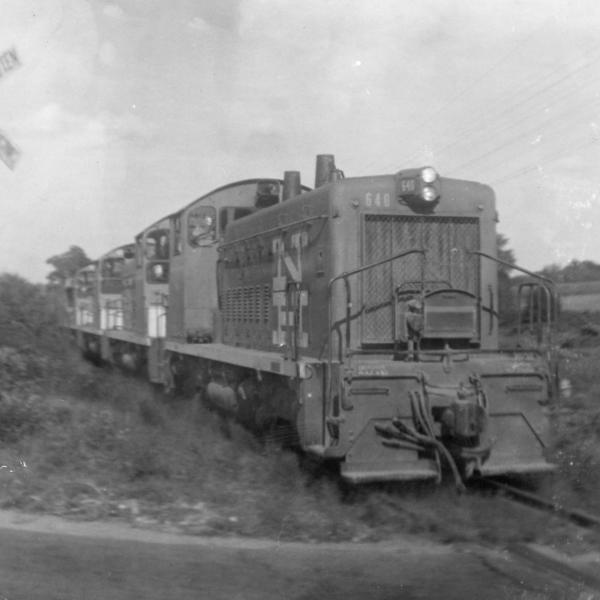 Four SW-1200s approaching level crossing