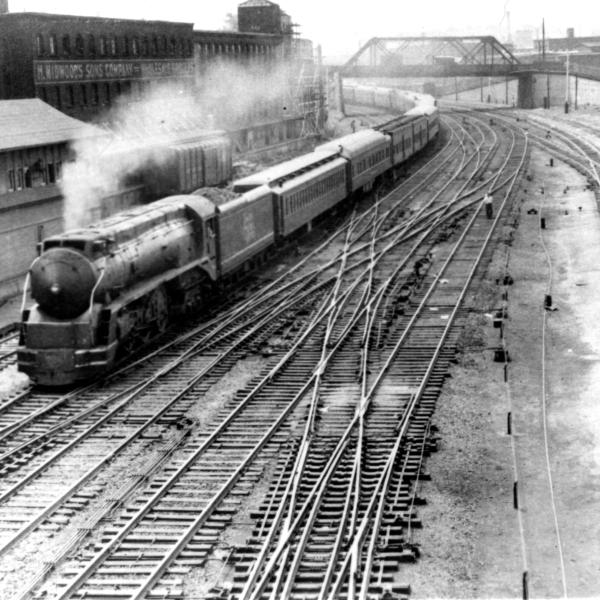 I-5 leads a long passenger train at S.S. 149, Brayton Ave Tower in Providence, RI.  Mix of Heavyweights, troop sleepers, and American Flyer cars in the consist
