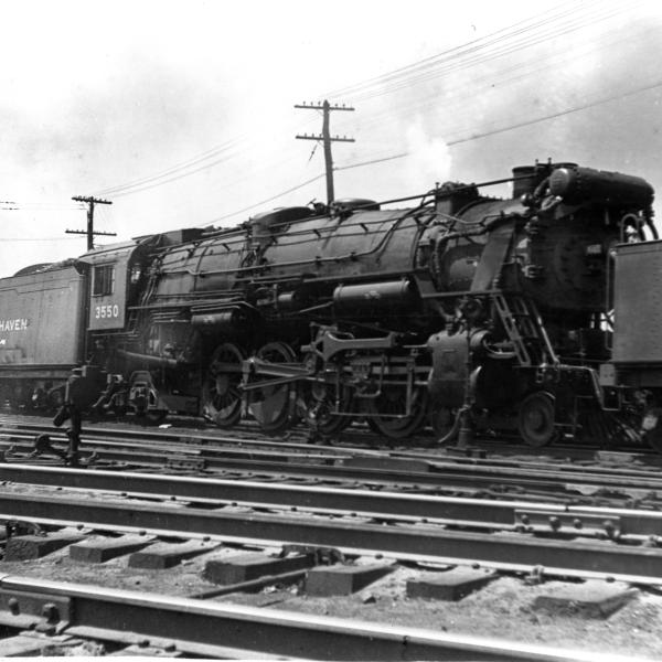 Engineer's side view of R-3  #3550 under steam between two light pacifics